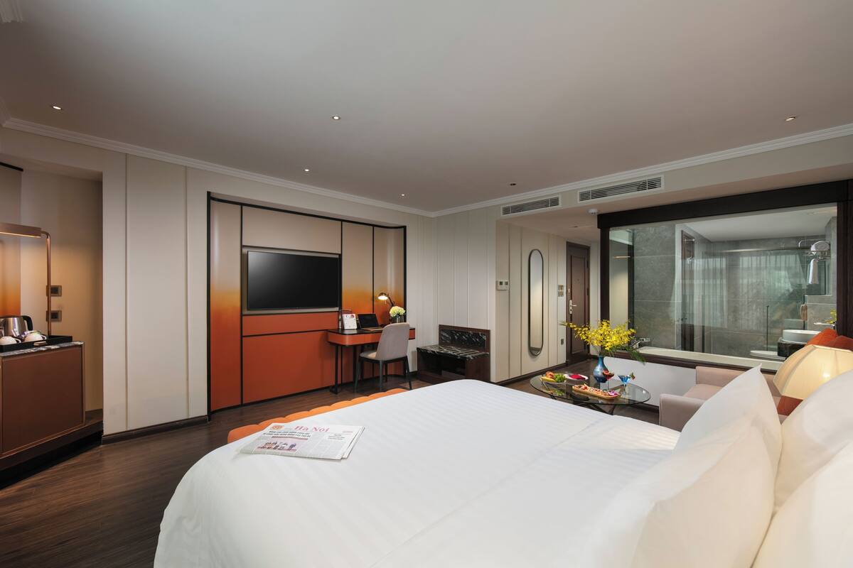 Une chambre d’hôtel avec un grand lit, un bureau avec une chaise, une télévision et une salle de bain avec douche.