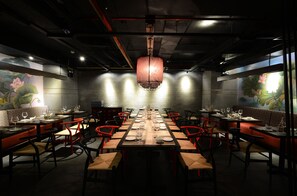 Un restaurante con una larga mesa dispuesta para una comida, rodeada de sillas rojas.