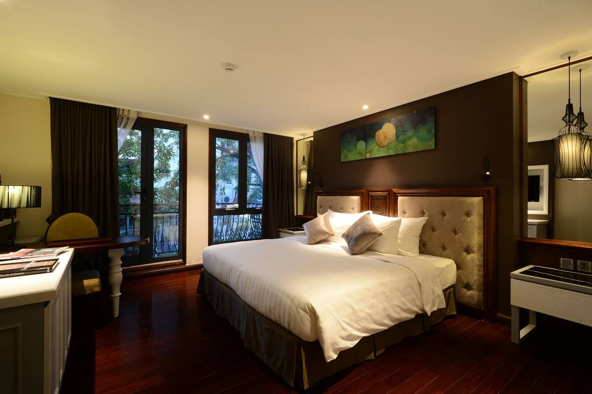 Une chambre à coucher avec un grand lit, un bureau, une chaise et une fenêtre avec des rideaux.