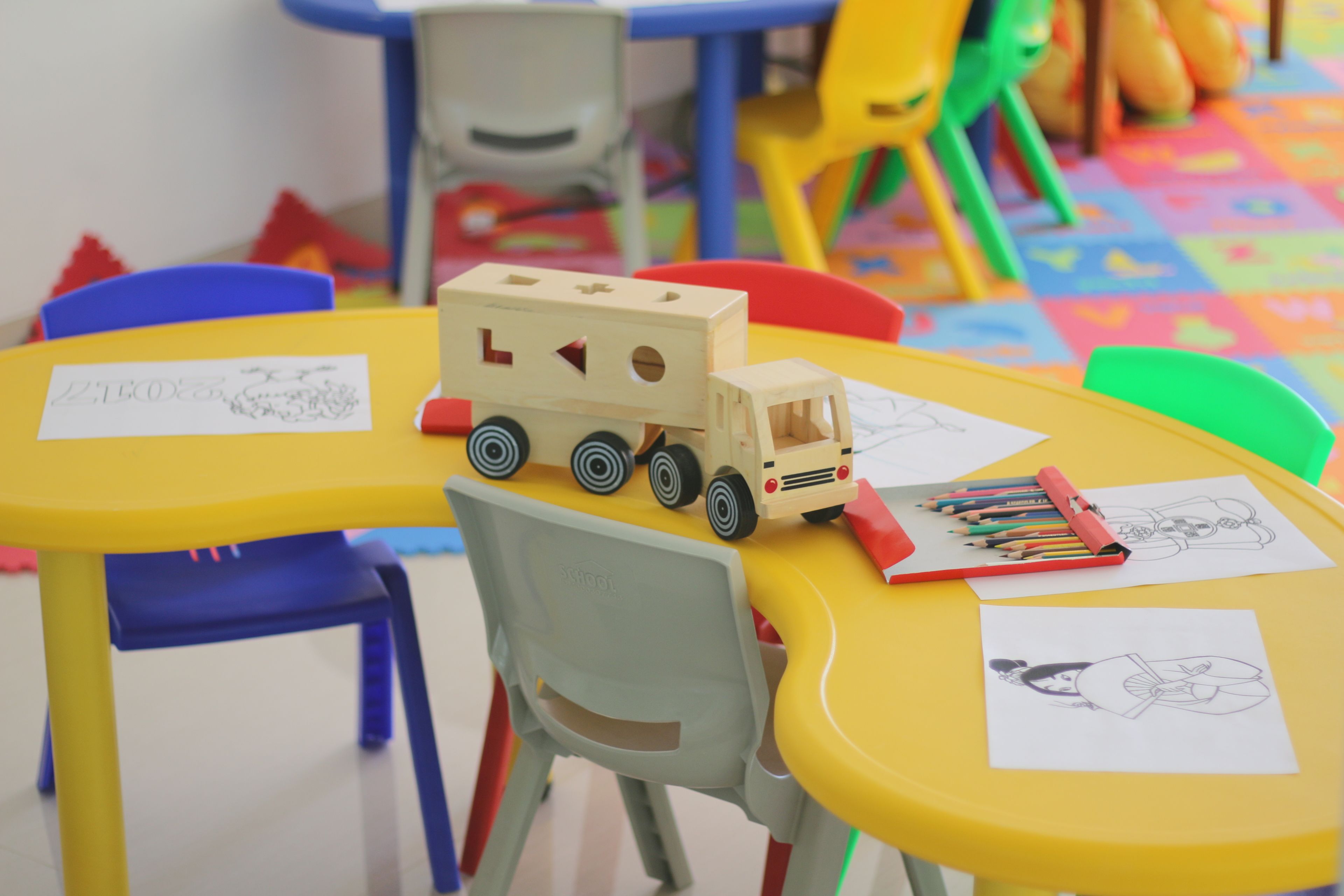Ein Tisch mit einem Spielzeug-Lkw, Kinderzeichnungen und Buntstiften.