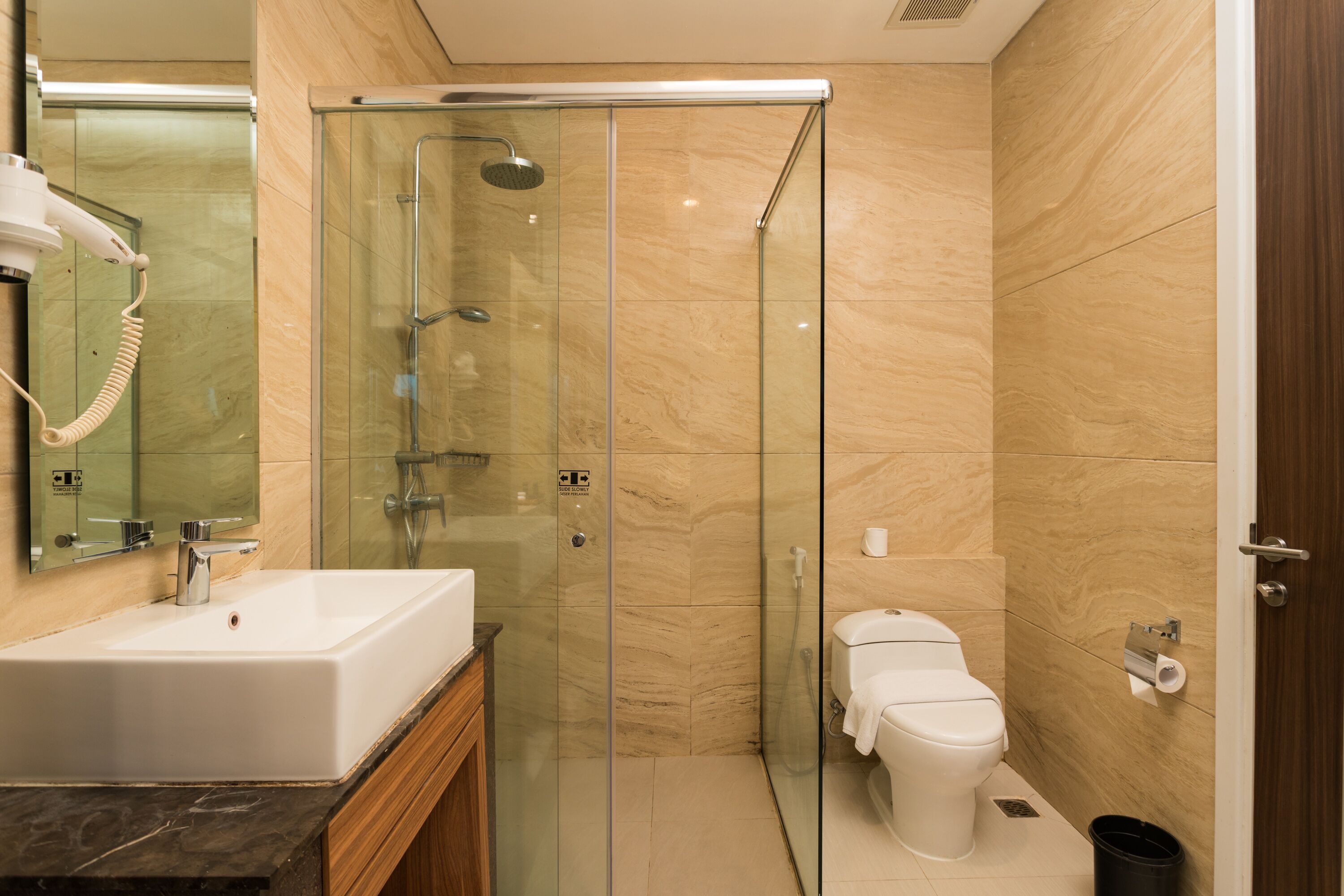A modern bathroom with a glass-enclosed shower, a white sink, and a toilet.