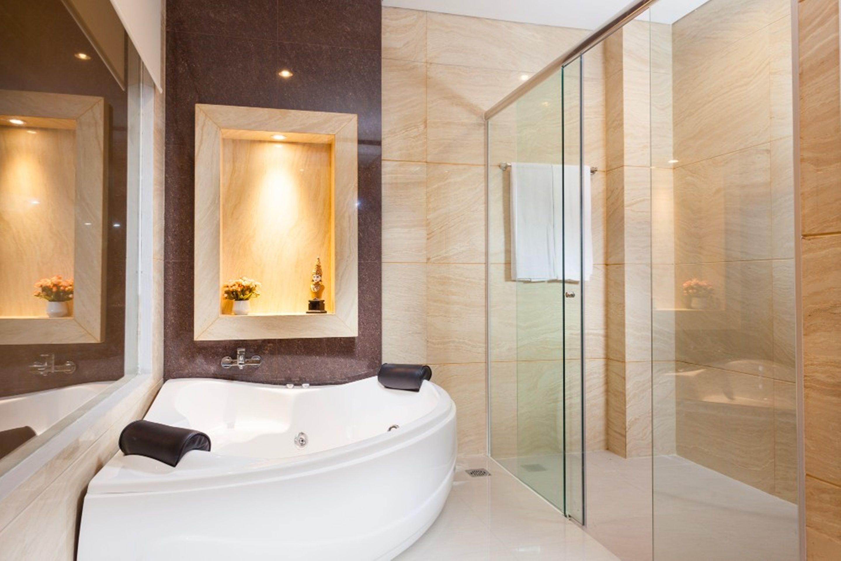 A modern bathroom with a large freestanding bathtub, a glass-enclosed shower, and a marble-tiled wall.
