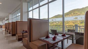 A hotel lobby with seating areas, large windows, and a view of a hilly landscape.