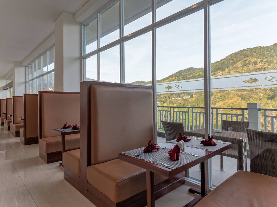A hotel lobby with seating areas, large windows, and a view of a hilly landscape.
