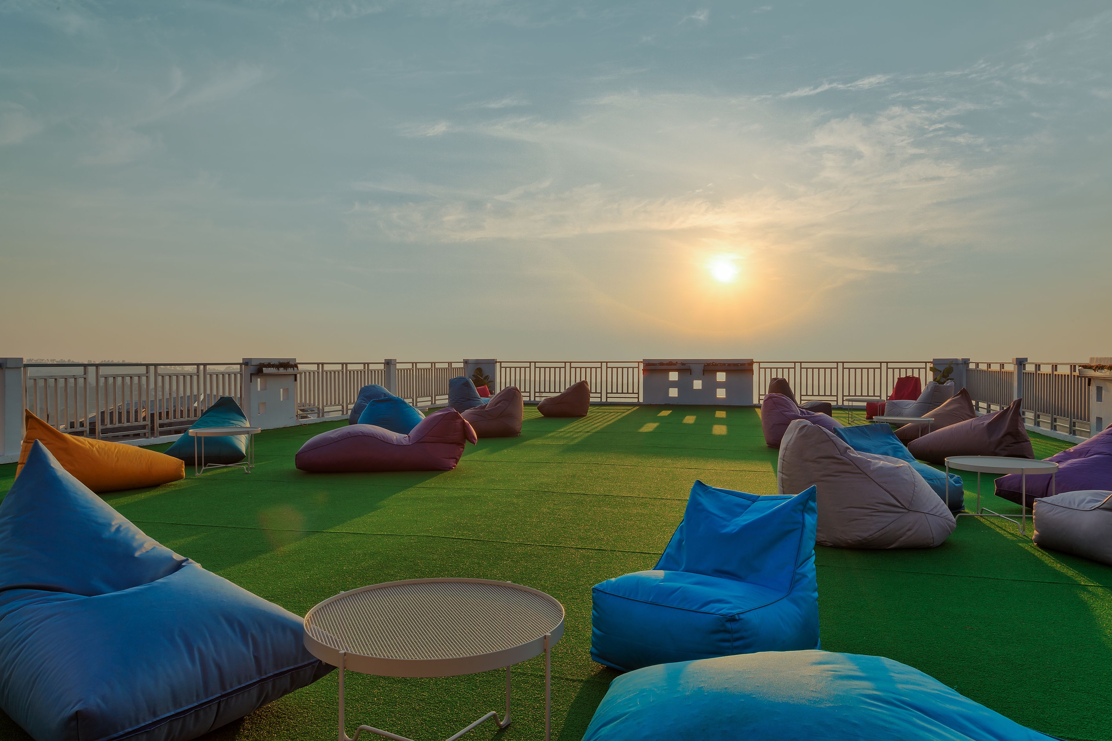 An outdoor seating area with green turf, multiple bean bags, and a small round table.