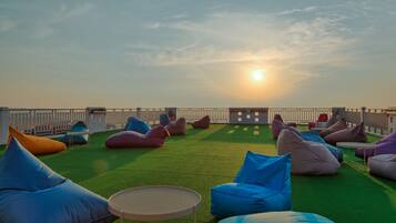 An outdoor seating area with green turf, multiple bean bags, and a small round table.