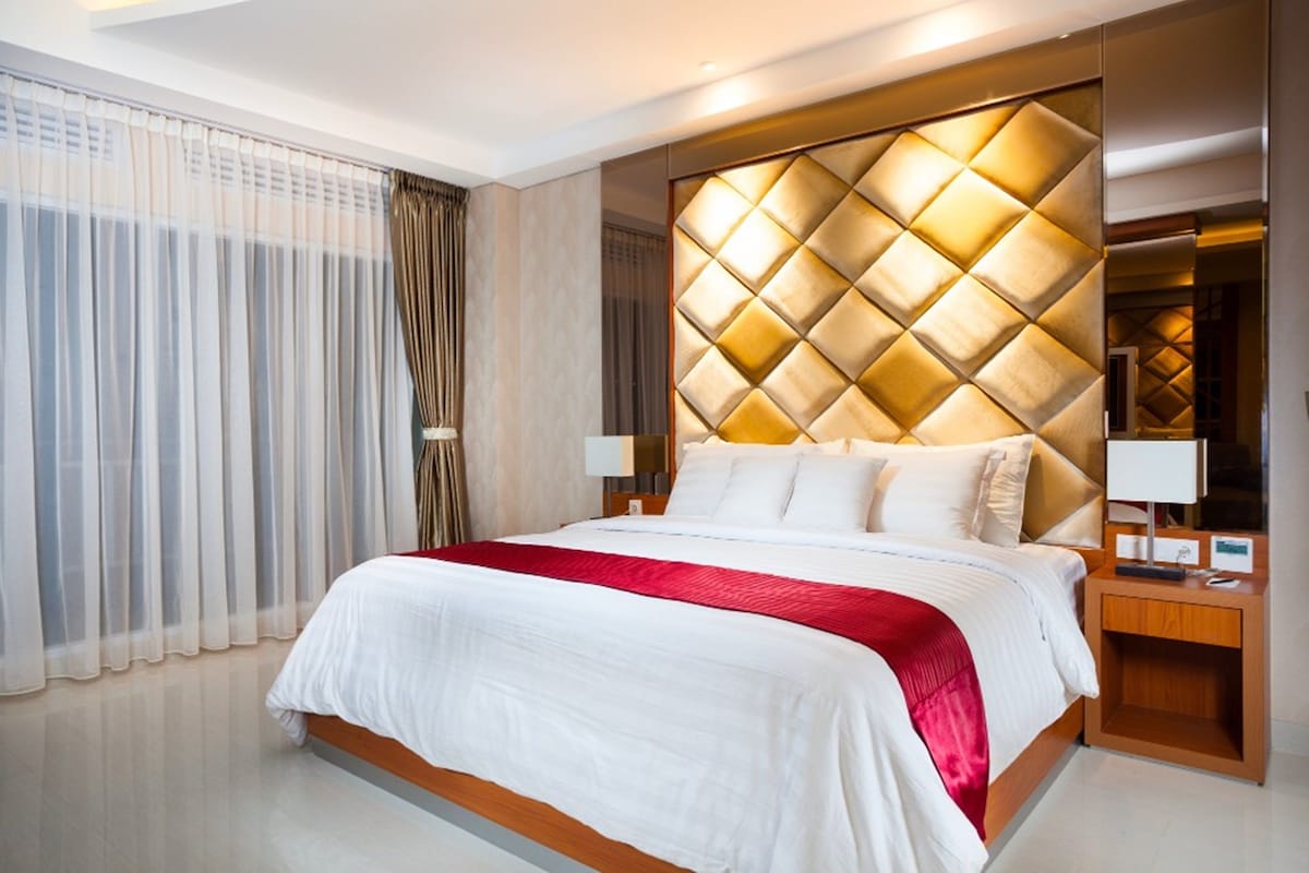 Una habitación de hotel con una cama grande, un cabecero de madera y una mesita de noche con una lámpara.