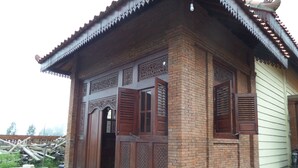 A traditional brick building with wooden doors and shutters, featuring intricate carvings and a tiled roof. - Villa Adas (Ngadisari)