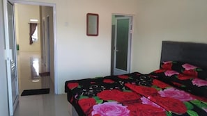 A bedroom with a bed, a door, and a mirror on the wall. - Villa Adas (Ngadisari)