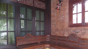 A traditional room with a wooden bench and table, large windows, and a brick wall. - Villa Adas (Ngadisari)