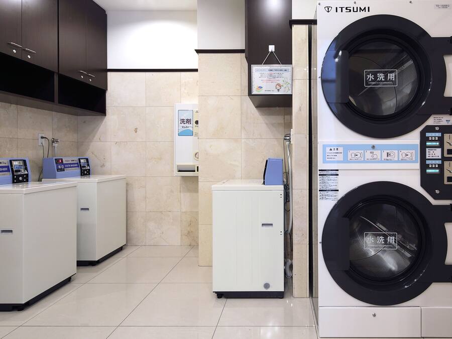 A laundry facility with two washing machines, a small refrigerator, and a water dispenser.