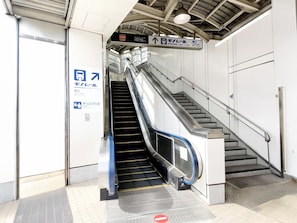 Un escalier mécanique à l’arrêt mène à un escalier, et une signalisation indique la direction à suivre pour se rendre à la porte sud.