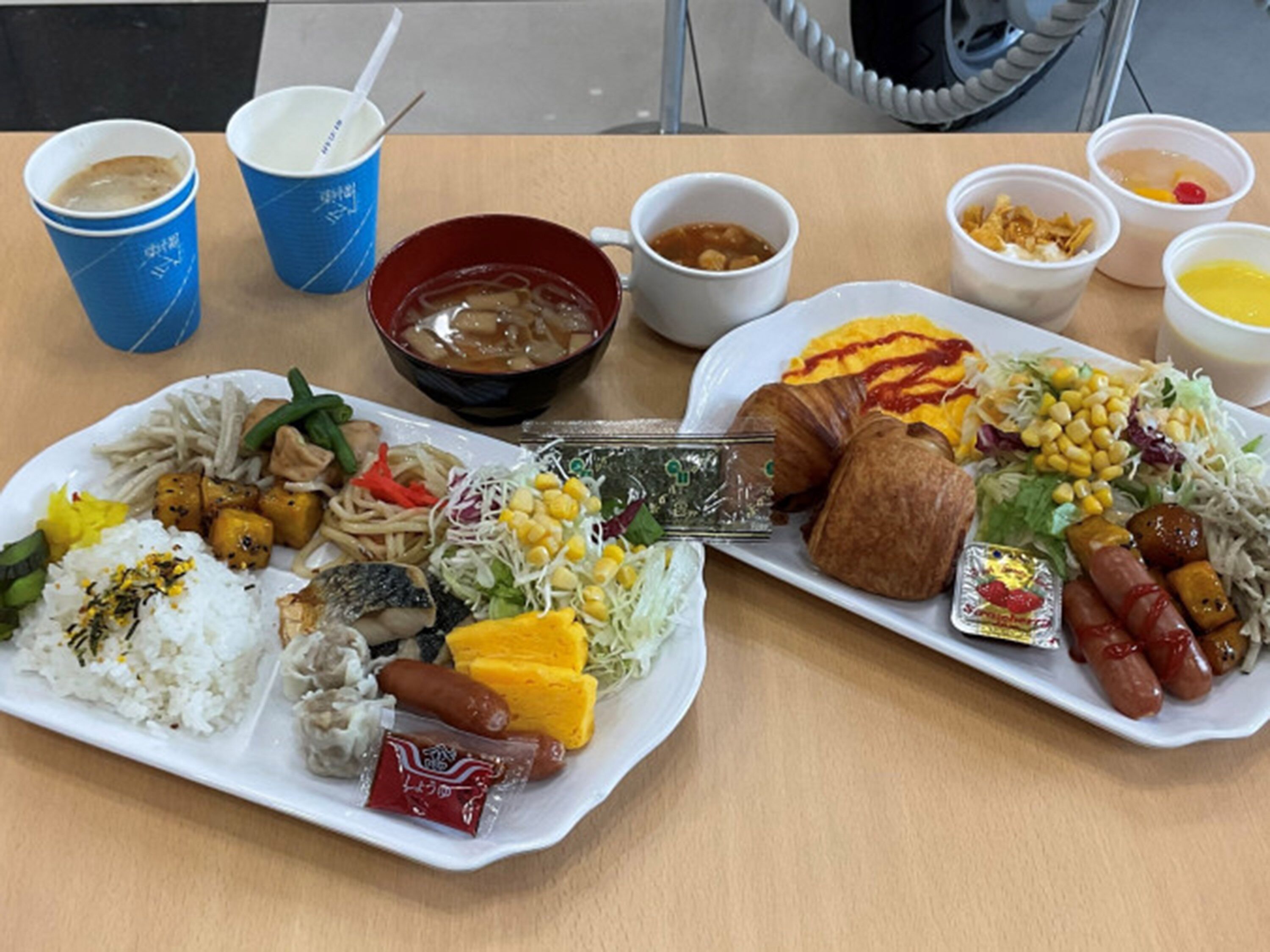 A table with various dishes including rice, vegetables, and meats, along with several cups and bowls.