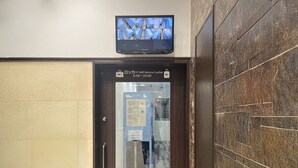 Entree van een hotelkamer met een digitaal scherm boven de deur, een selfservice locker en uitzicht op de binnenhal.