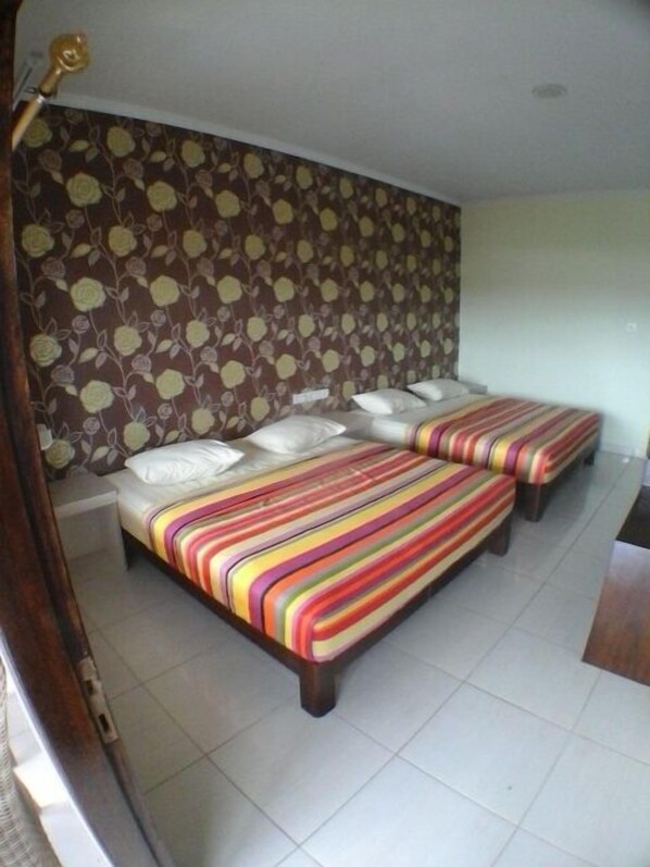 A room with a bed, two bedside tables, and a patterned wall. - Holiday Beach Inn (Pangandaran)