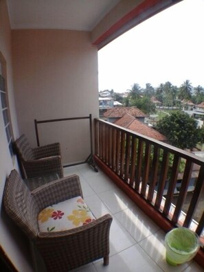 A balcony with wicker furniture and a green trash bin. - Holiday Beach Inn (Pangandaran)