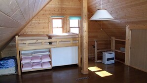 A wooden attic bedroom with a bunk bed, a desk, and a hanging light fixture. - Cottage Primal Stage (Kamishihoro)