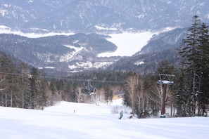 Ein Skigebiet mit Sessellift, schneebedeckten Pisten und einer Ortschaft im Tal.
