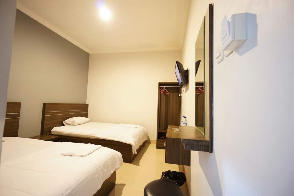 Quarto de hotel com duas camas, televisão, espelho e pequena escrivaninha.