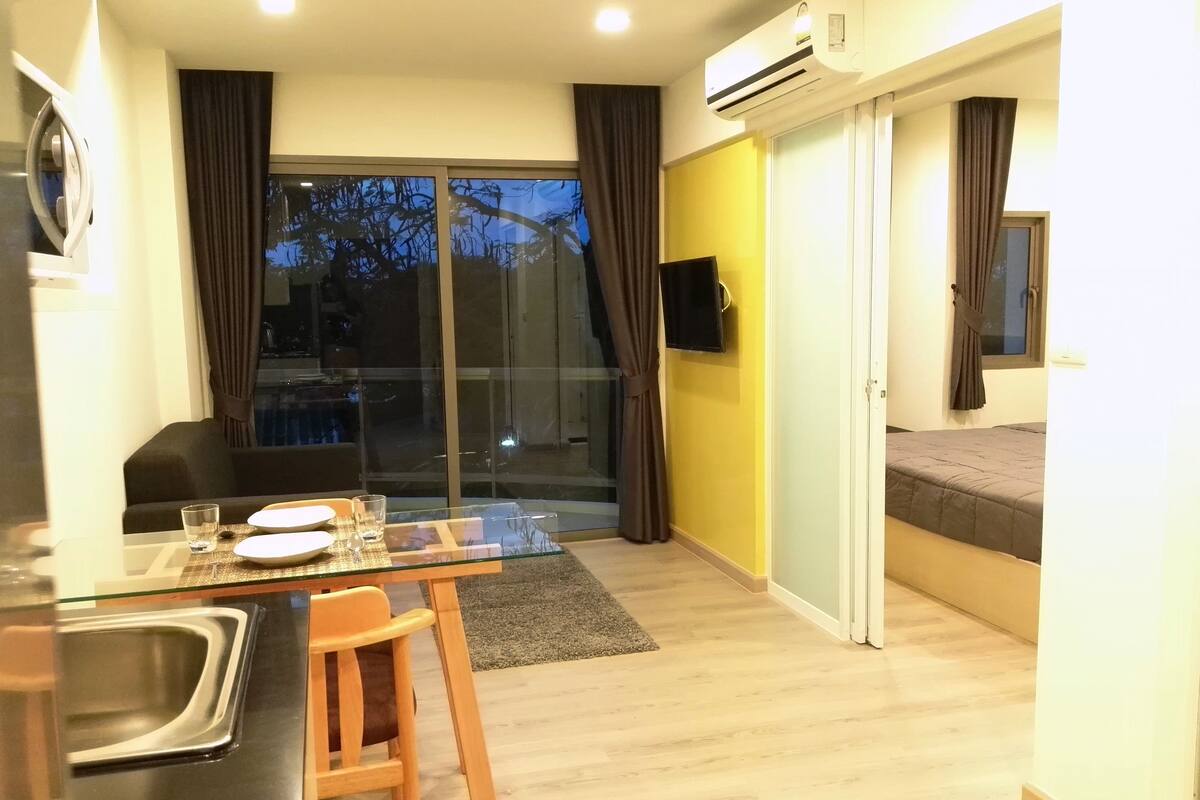 Un espacio habitable compacto con comedor, kitchenette y dormitorio.