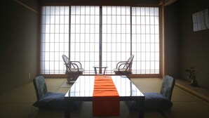 A tatami mat room with a low table, two chairs, and a large window. - Yukeikohan Suitenkaku (Matsue)