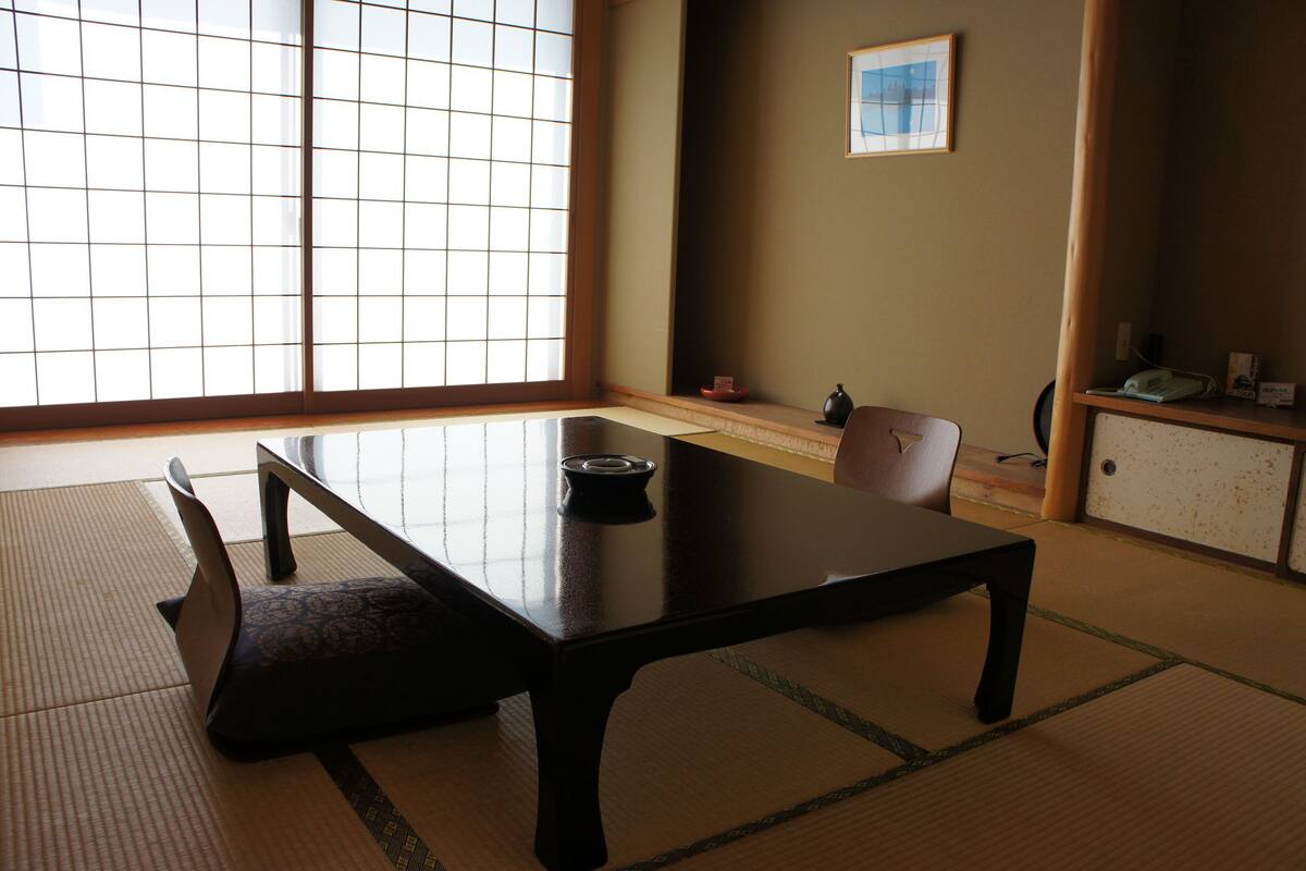 A traditional Japanese room with tatami flooring, a low table, and a sliding door.