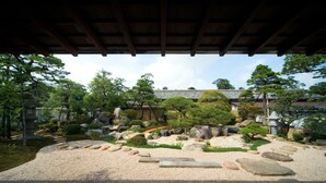 A traditional Japanese garden with a stone pathway, rocks, and trees. - Yukeikohan Suitenkaku (Matsue)