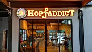 Un restaurant appelé HopFaddict, doté d’un intérieur moderne, de tables bien visibles et d’une façade en verre transparent.