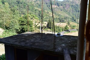 A view from a building's roof overlooking a rural landscape with trees and a few houses.