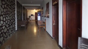 A hallway with a patterned wall, a wooden door with a sign, and a tiled floor. - Losmen Adas (Ngadisari)