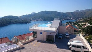 A hotel with a swimming pool, parking area, and a view of the sea and mountains. - Villa Paradiso 2 (Dubrovnik)