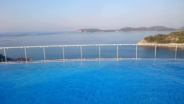 A swimming pool with a view of the sea and distant islands.