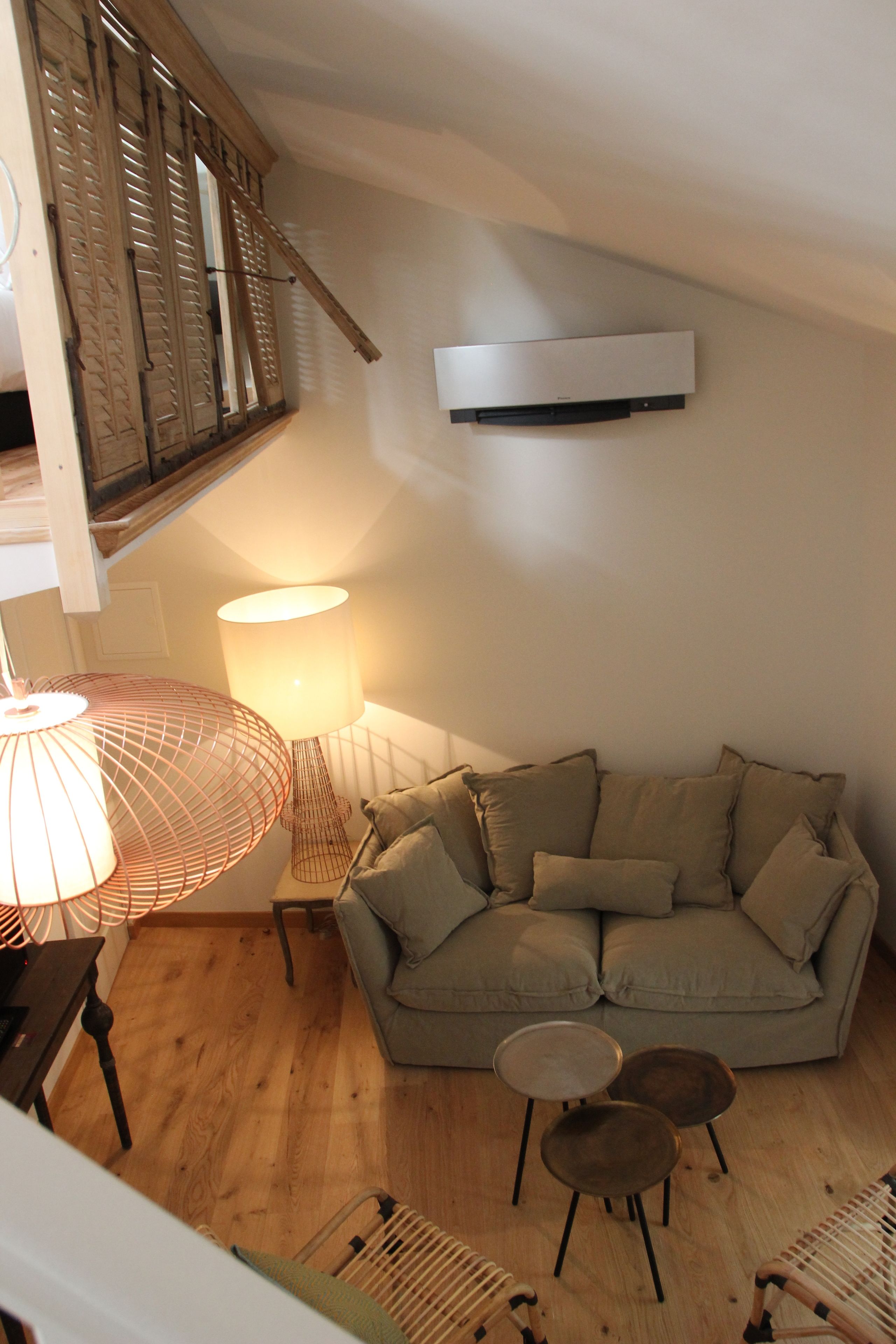 Un salon chaleureux avec un canapé, deux tables d’appoint, une lampe et un plancher en bois.