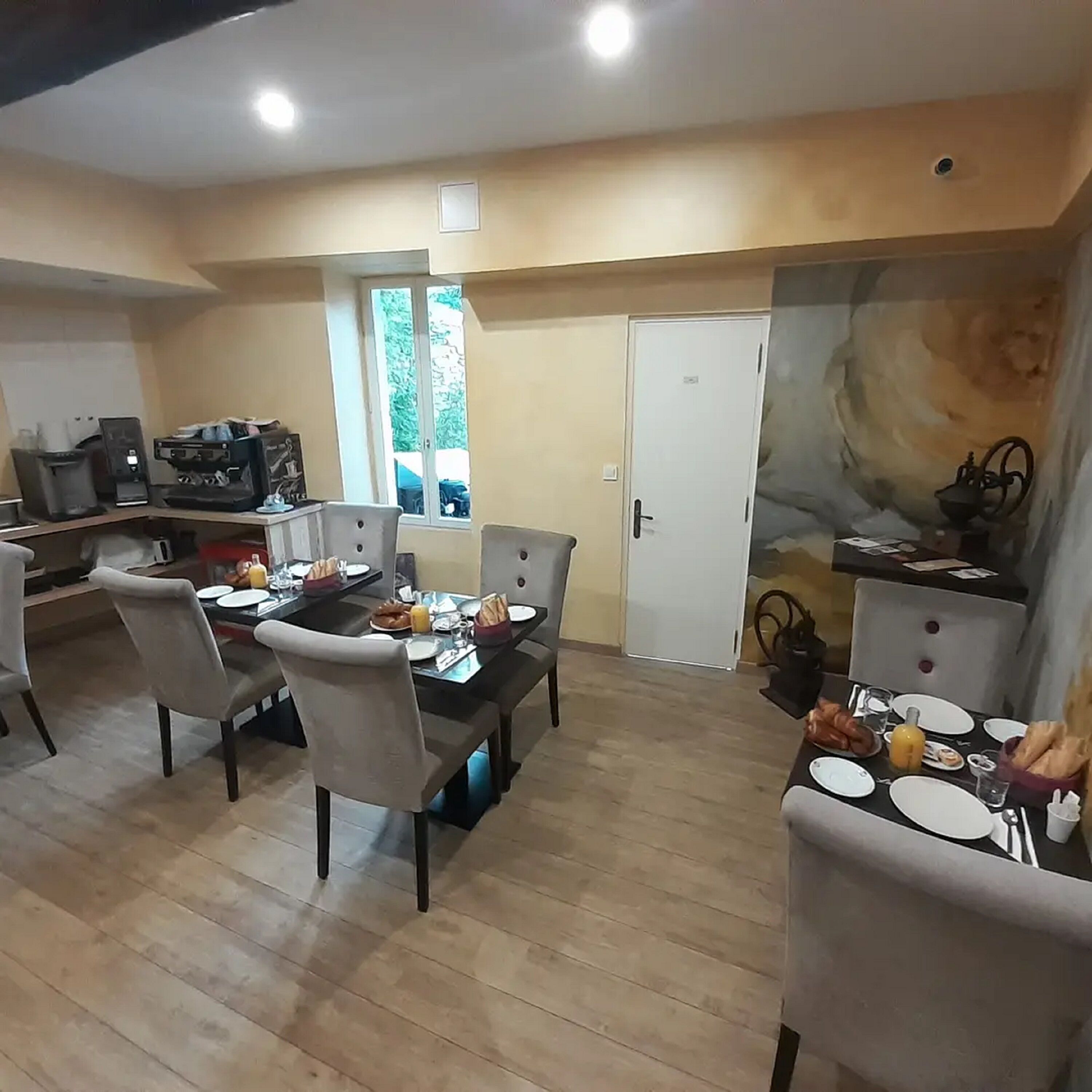 A dining area with a table set for four, chairs, and a coffee machine.