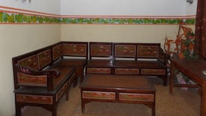 A room with a wooden bench and a table, a decorative border on the wall, and a framed picture above the bench. - Losmen Setia Kawan II (Ngadisari)