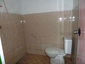 A small bathroom with a toilet, a shower, and tiled walls. - Losmen Setia Kawan II (Ngadisari)