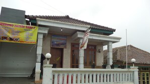 A building with a tiled roof, a porch with a railing, and a signboard. - Losmen Setia Kawan II (Ngadisari)