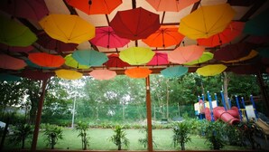 A covered outdoor area with colorful umbrellas hanging overhead. - Merlin Hotel (Port Dickson)