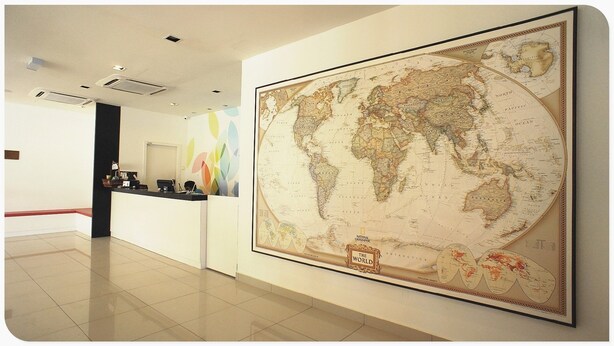 A lobby with a large world map, a reception desk, and a tiled floor. - Merlin Hotel (Port Dickson)