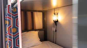 A single bed with white bedding, a headboard, and a wall-mounted light fixture.