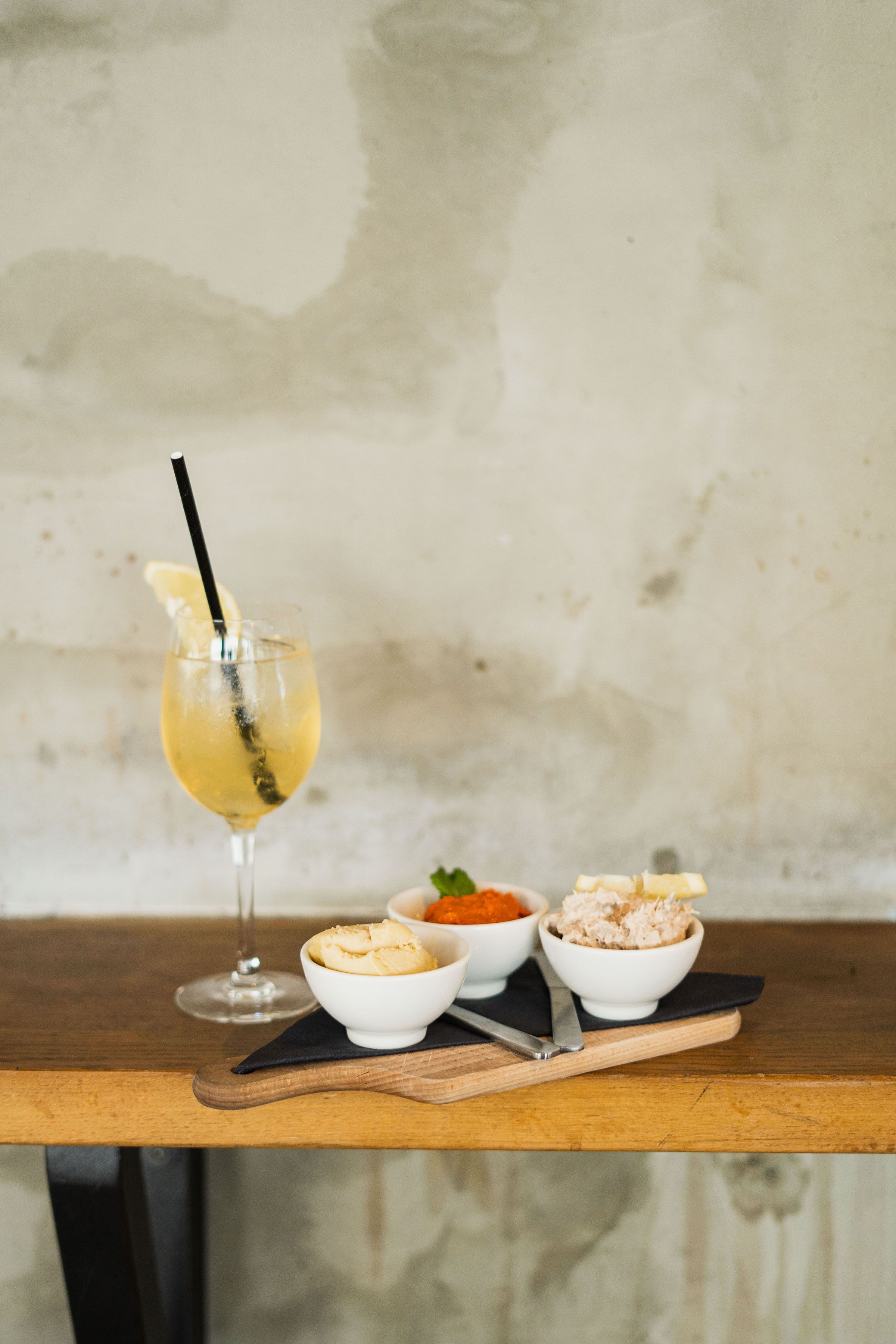 Ein Tisch mit einem Glas eines gelben Getränks, zwei Schalen Essen und einem Löffel auf einer Holzoberfläche.