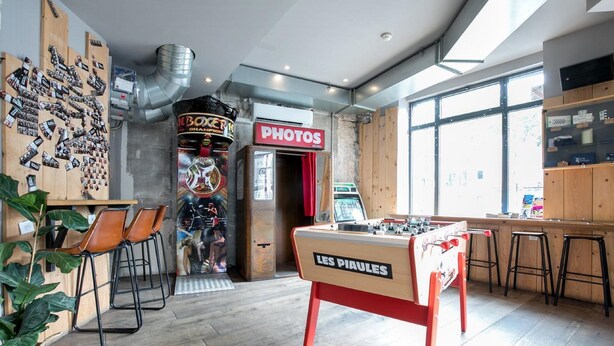 A cozy bar area with a foosball table, a photo booth, and a vintage arcade machine. - The People - Paris Belleville (ex Les Piaules) - Hostel (Paris)
