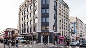 A multi-story building with a prominent entrance, a visible storefront, and a pedestrian crossing. - The People - Paris Belleville (ex Les Piaules) - Hostel (Paris)
