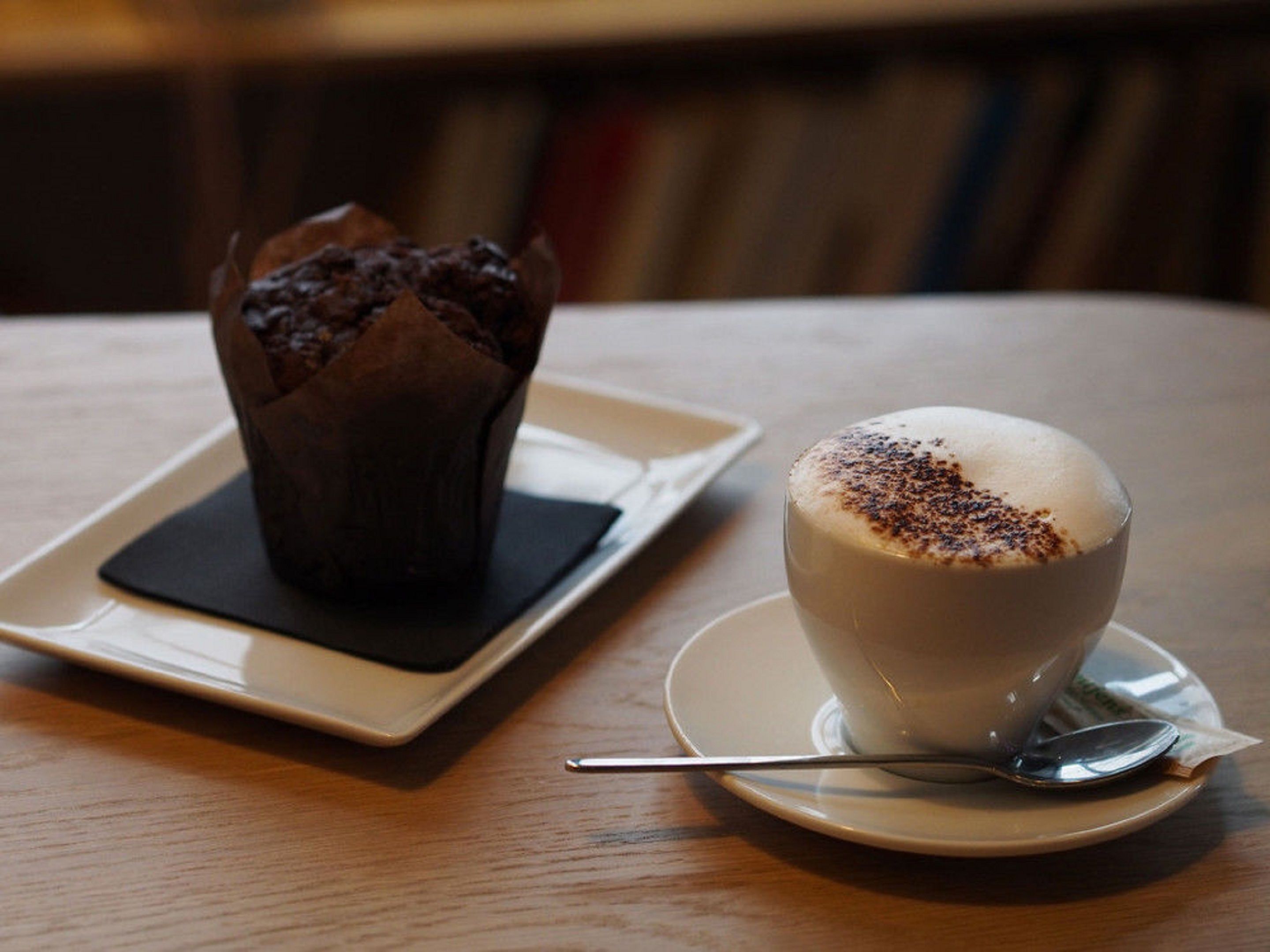 Un muffin i una tassa de cafè sobre una taula.