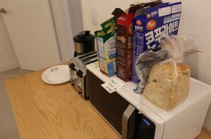 A kitchen counter with a toaster, a bag of bread, and various food items including milk cartons and a juice box. - DADAREUM Guest House (Seoul)