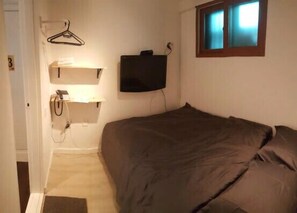 A small bedroom with a bed, a wall-mounted TV, a bedside table, and a hanging light. - DADAREUM Guest House (Seoul)