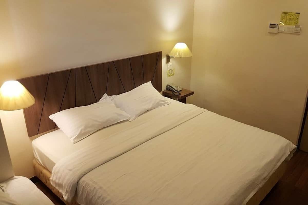 Habitación de hotel con cama, lámparas de noche, mesita de noche y una puerta con cerradura y panel de control.