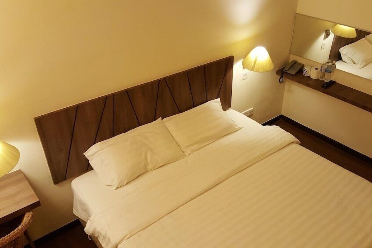 A hotel room with a bed, bedside lamps, a mirror, and a nightstand.