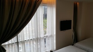 A hotel room with a bed, a TV mounted on the wall, and a window with sheer curtains. - 9 Square Hotel - Kota Damansara (Petaling Jaya)