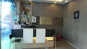 A reception area with a desk, two chairs, a mirror, and a wall with a textured pattern. - 9 Square Hotel - Kota Damansara (Petaling Jaya)